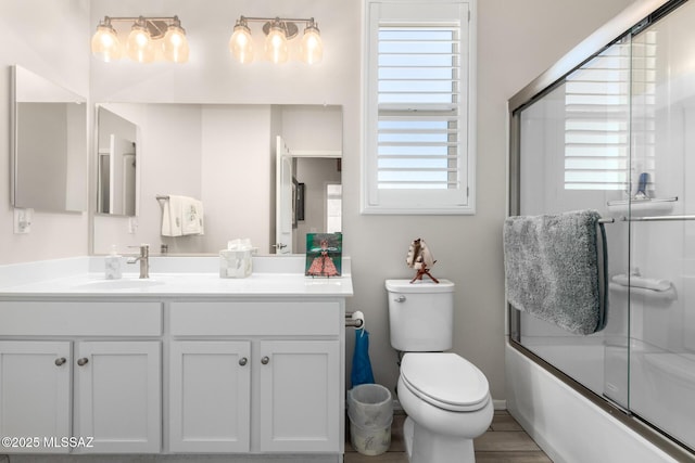 full bathroom featuring toilet, vanity, and bath / shower combo with glass door