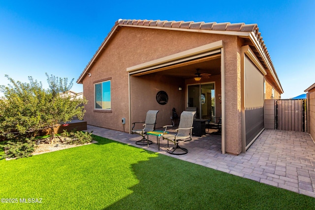 rear view of property with ceiling fan, a yard, and a patio