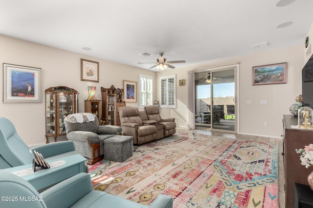 living area featuring baseboards, visible vents, and a ceiling fan