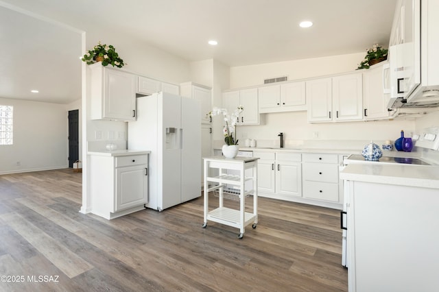 kitchen with sink, hardwood / wood-style floors, white fridge with ice dispenser, and white cabinets