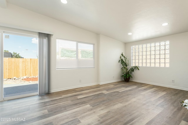 spare room with lofted ceiling, light hardwood / wood-style floors, and a wealth of natural light