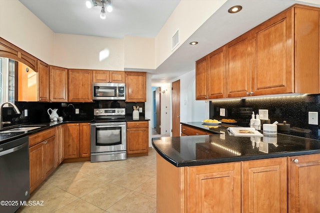 kitchen with a towering ceiling, stainless steel appliances, sink, kitchen peninsula, and light tile patterned flooring