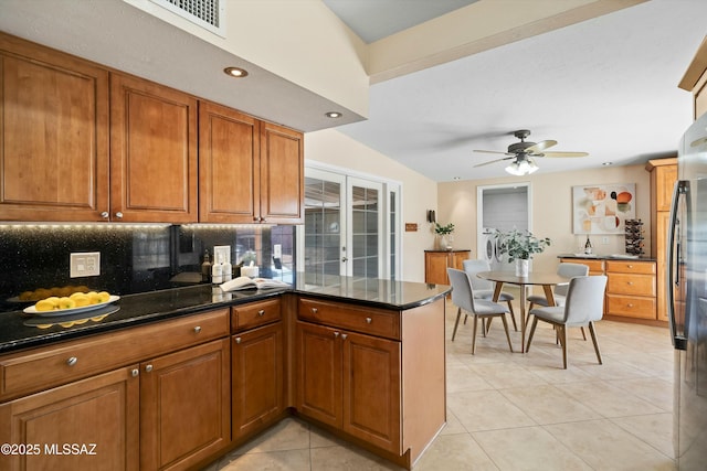 kitchen with french doors, backsplash, kitchen peninsula, stainless steel refrigerator, and light tile patterned floors