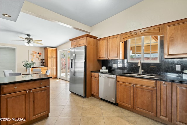 kitchen with sink, light tile patterned flooring, dark stone countertops, decorative backsplash, and stainless steel appliances