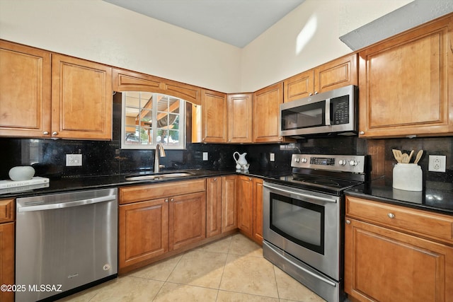 kitchen featuring appliances with stainless steel finishes, dark stone countertops, sink, backsplash, and light tile patterned floors