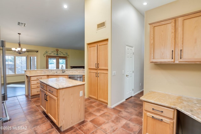 kitchen with light brown cabinetry, sink, hanging light fixtures, and a kitchen island