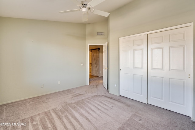 unfurnished bedroom featuring ceiling fan, light colored carpet, and a closet