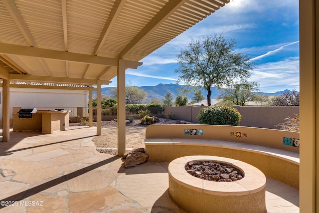 view of patio featuring a mountain view, an outdoor fire pit, and an outdoor kitchen