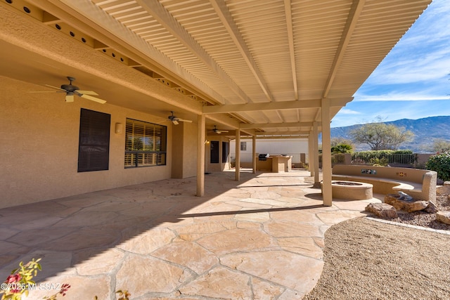 view of patio / terrace featuring ceiling fan, a mountain view, and a fire pit