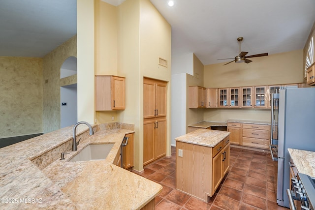 kitchen with light stone counters, sink, stainless steel refrigerator, and a kitchen island