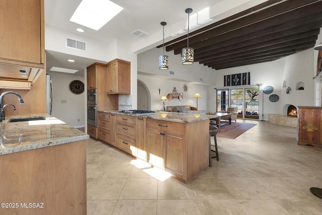 kitchen with pendant lighting, sink, a breakfast bar area, light stone counters, and kitchen peninsula