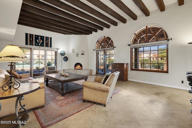 living room with a towering ceiling, a fireplace, beam ceiling, and light tile patterned floors