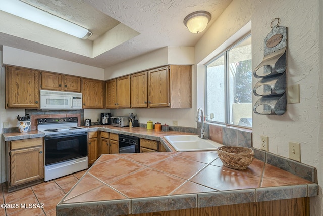 kitchen featuring sink, a textured ceiling, light tile patterned floors, electric range, and tile counters