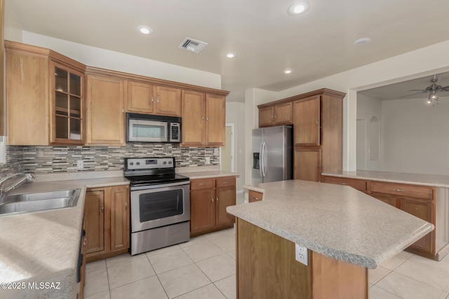 kitchen featuring sink, tasteful backsplash, light tile patterned floors, a center island, and stainless steel appliances