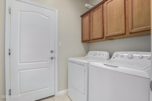 laundry room with light tile patterned floors, cabinets, and washer and dryer