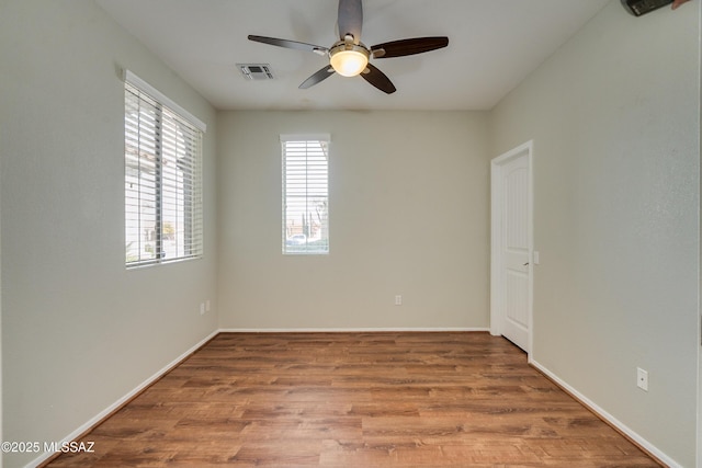 spare room with a wealth of natural light, hardwood / wood-style floors, and ceiling fan