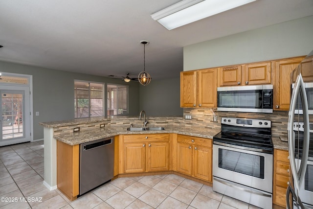 kitchen featuring appliances with stainless steel finishes, sink, hanging light fixtures, light stone counters, and kitchen peninsula