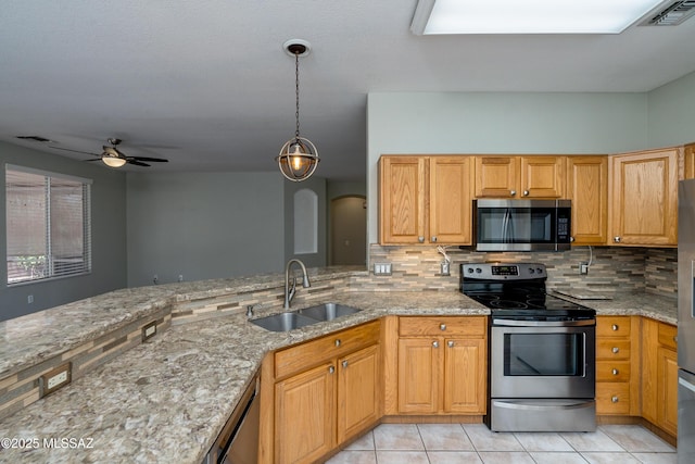 kitchen featuring sink, hanging light fixtures, stainless steel appliances, light stone countertops, and decorative backsplash