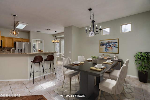 dining space featuring light tile patterned floors, sink, and a chandelier