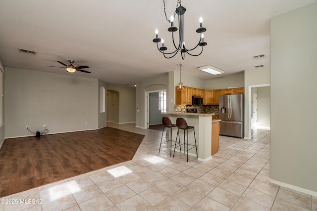 kitchen with stainless steel refrigerator with ice dispenser, light tile patterned flooring, backsplash, and light stone counters