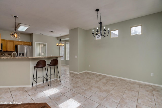 kitchen featuring light tile patterned floors, a notable chandelier, light stone counters, and stainless steel fridge with ice dispenser