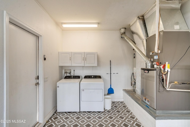 clothes washing area with heating unit, cabinets, and washer and dryer