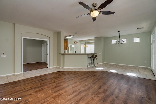 unfurnished living room featuring ceiling fan with notable chandelier and light tile patterned floors