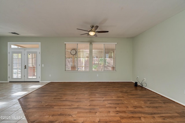 tiled empty room featuring french doors and ceiling fan