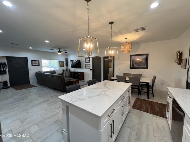 kitchen featuring dishwasher, white cabinets, a kitchen island, pendant lighting, and light stone counters