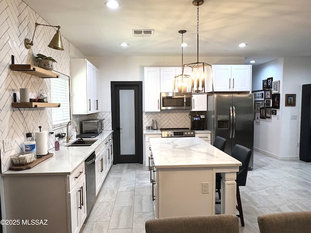 kitchen featuring stainless steel appliances, white cabinetry, and a kitchen island