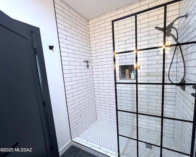 bathroom with tiled shower and tile patterned flooring