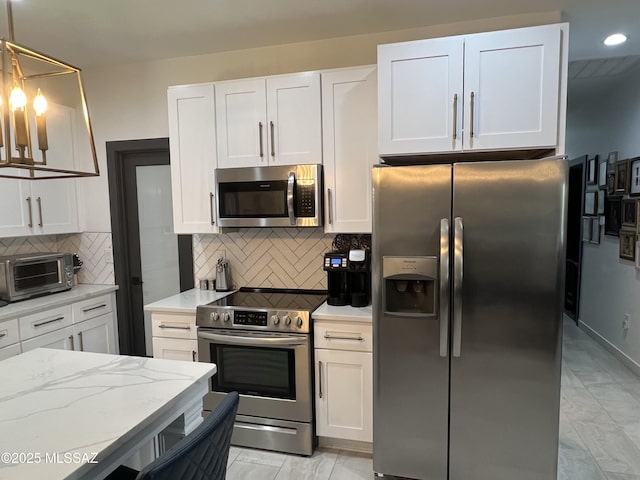 kitchen featuring decorative backsplash, decorative light fixtures, white cabinetry, and appliances with stainless steel finishes