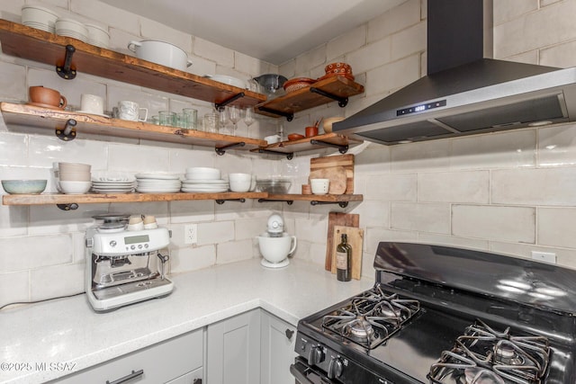 kitchen with wall chimney exhaust hood, black range with gas stovetop, and decorative backsplash