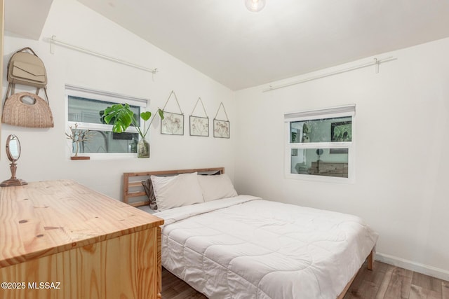 bedroom with hardwood / wood-style flooring, vaulted ceiling, and multiple windows