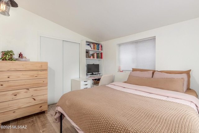 bedroom with vaulted ceiling, a closet, and wood-type flooring