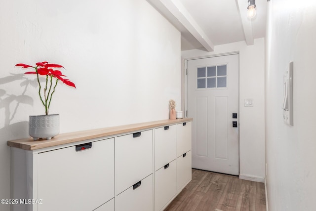 doorway featuring beamed ceiling and light hardwood / wood-style flooring