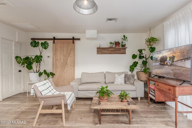 living room featuring a barn door and light hardwood / wood-style flooring