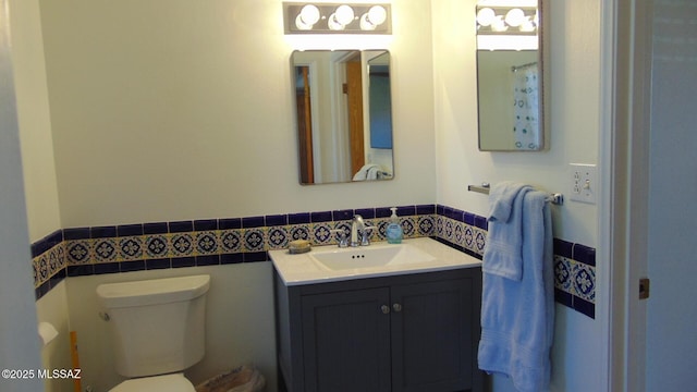 bathroom with vanity, toilet, and tile walls