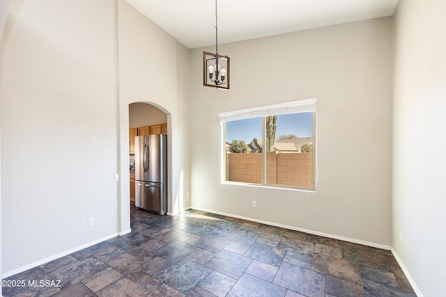 unfurnished room featuring an inviting chandelier and a towering ceiling