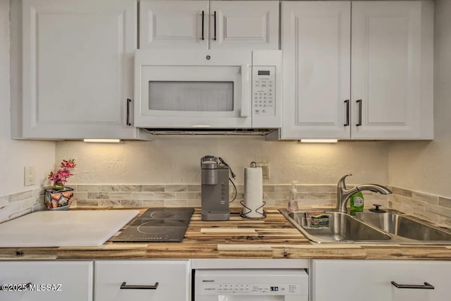 kitchen featuring washer / dryer, sink, tasteful backsplash, dishwasher, and white cabinets