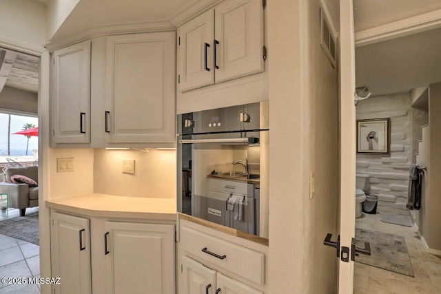 kitchen featuring white cabinetry, light tile patterned flooring, and oven