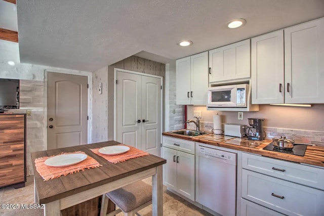 kitchen with white cabinetry, sink, white appliances, and wooden counters