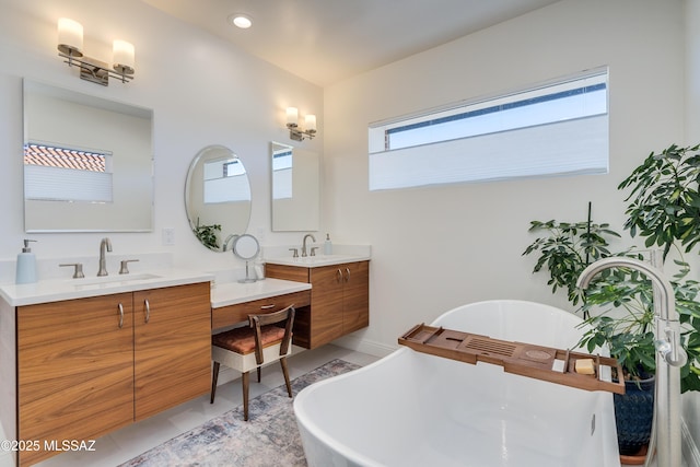 full bath with a sink, a freestanding bath, and two vanities