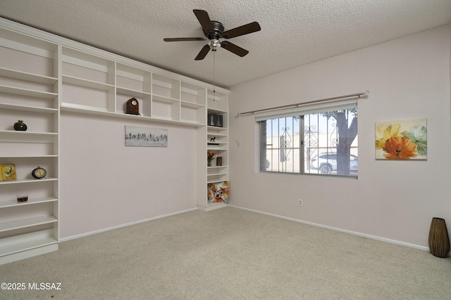 carpeted empty room with ceiling fan, a textured ceiling, and baseboards