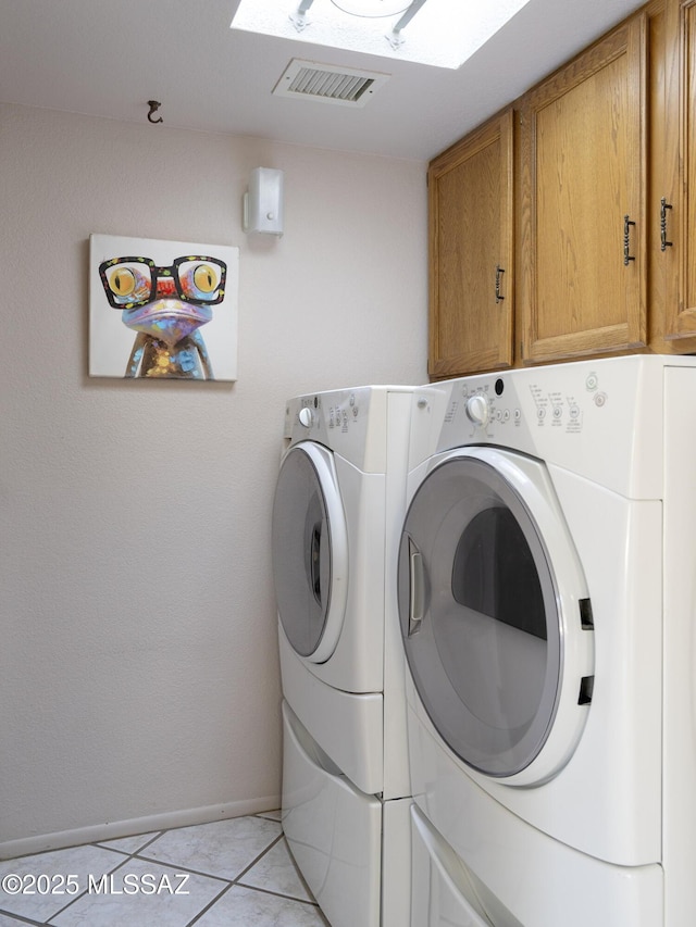 laundry area with light tile patterned floors, visible vents, baseboards, cabinet space, and washing machine and clothes dryer