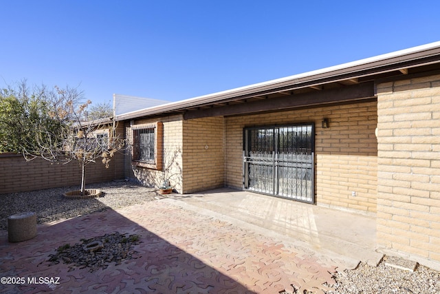 exterior space featuring brick siding, a patio area, and fence