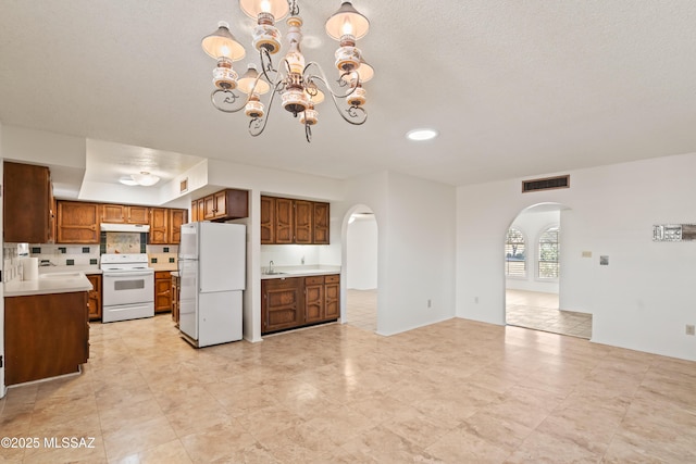 kitchen featuring white appliances, a chandelier, sink, and hanging light fixtures