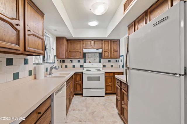 kitchen with sink, white appliances, a raised ceiling, and backsplash