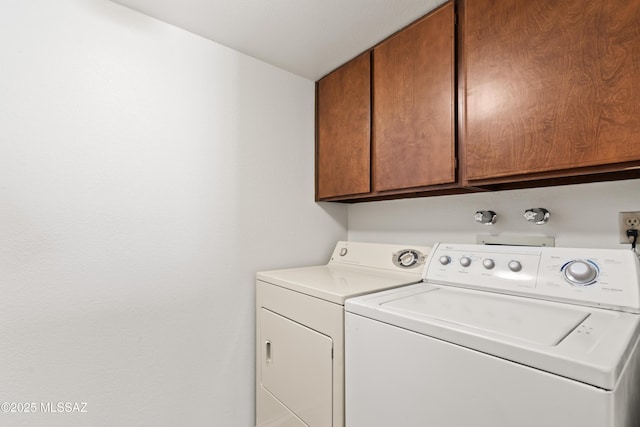 clothes washing area featuring separate washer and dryer and cabinets