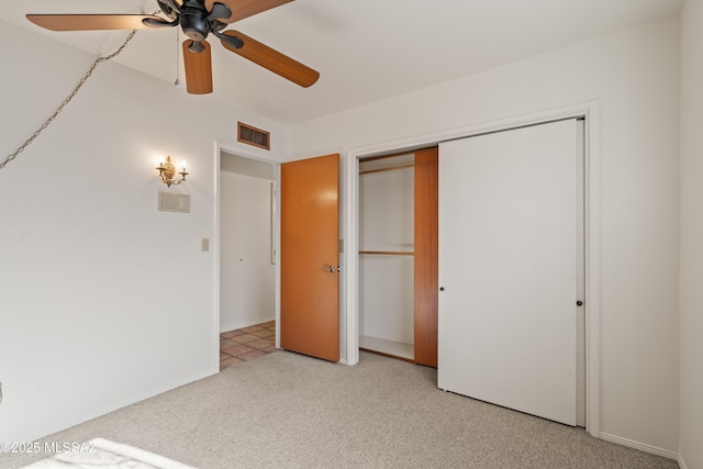 unfurnished bedroom with light carpet, a closet, and ceiling fan